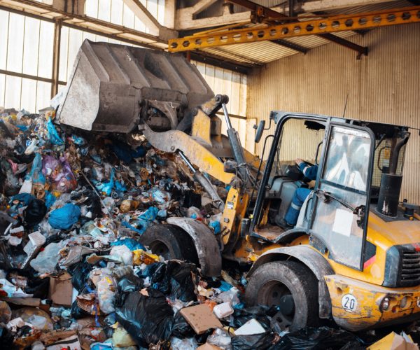 An excavator working with a heap of garbage at waste sorting plant